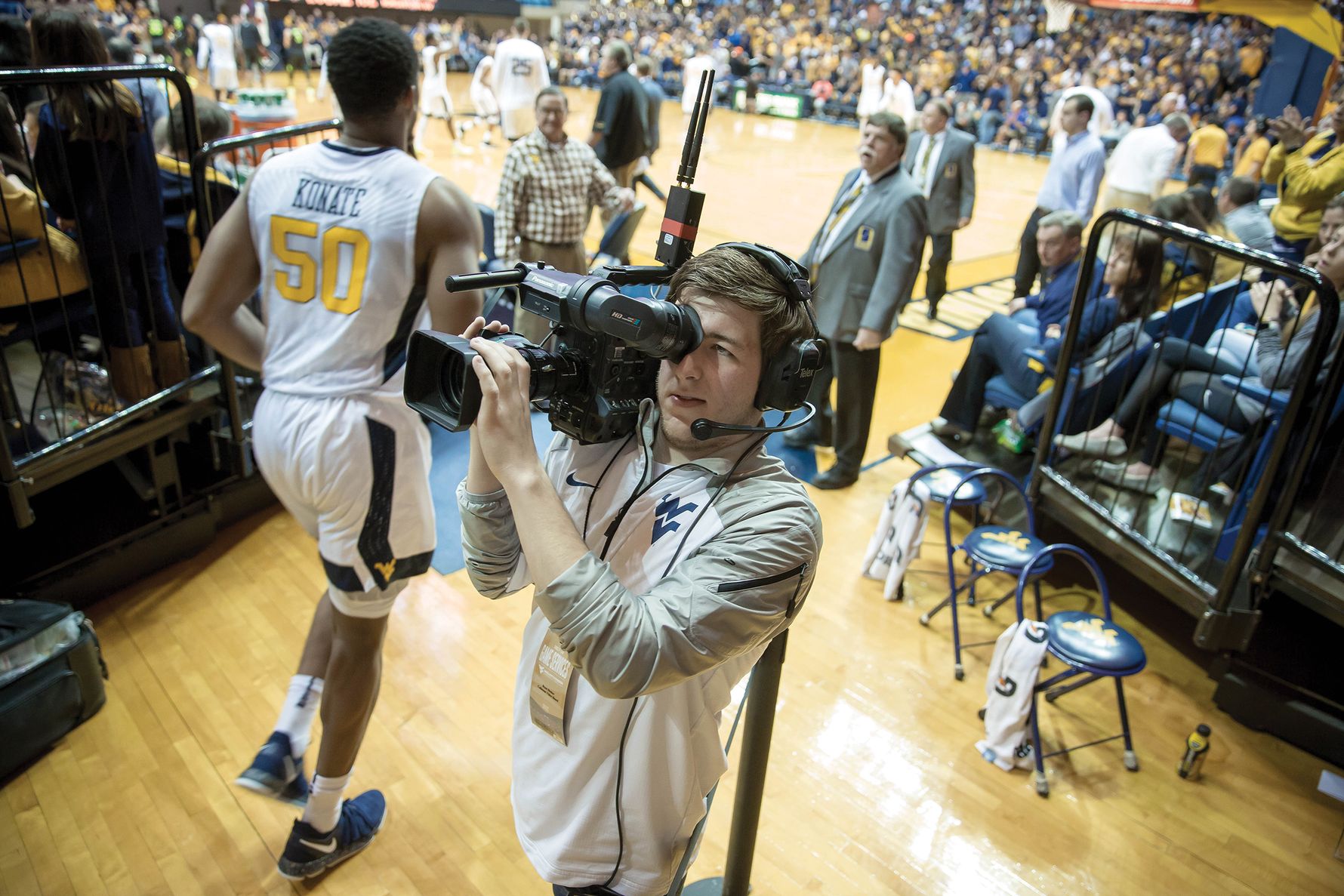 Man with video camera shooting basketball players entering the basketball arena