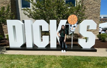 Kaitlyn Lopez stands in front of a sign that says DICK'S Sporting Goods 