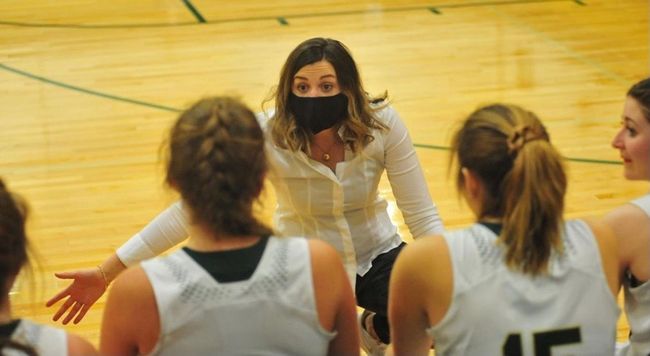 A woman coaches girls varsity basketball 